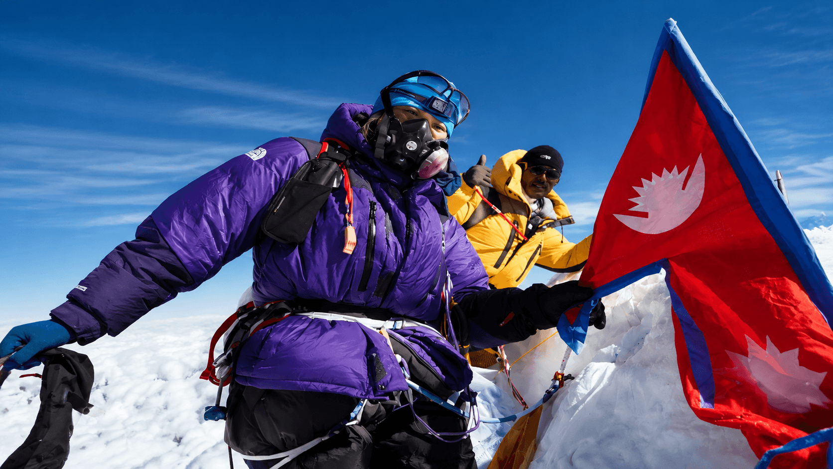 Mountaineers celebrating on a summit with the Nepal flag.